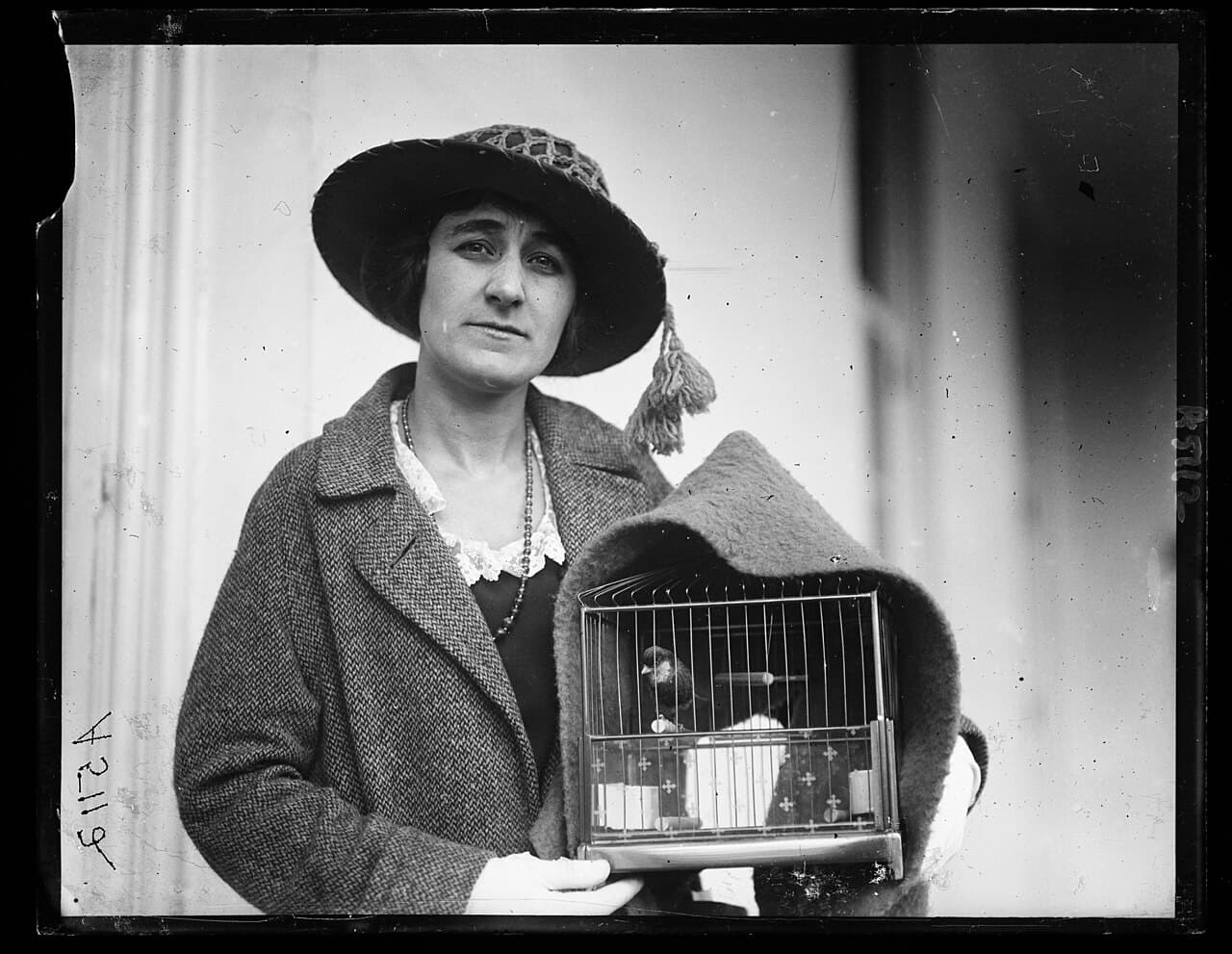 Historic black-and-white photo of a woman holding a cage with a roller canary